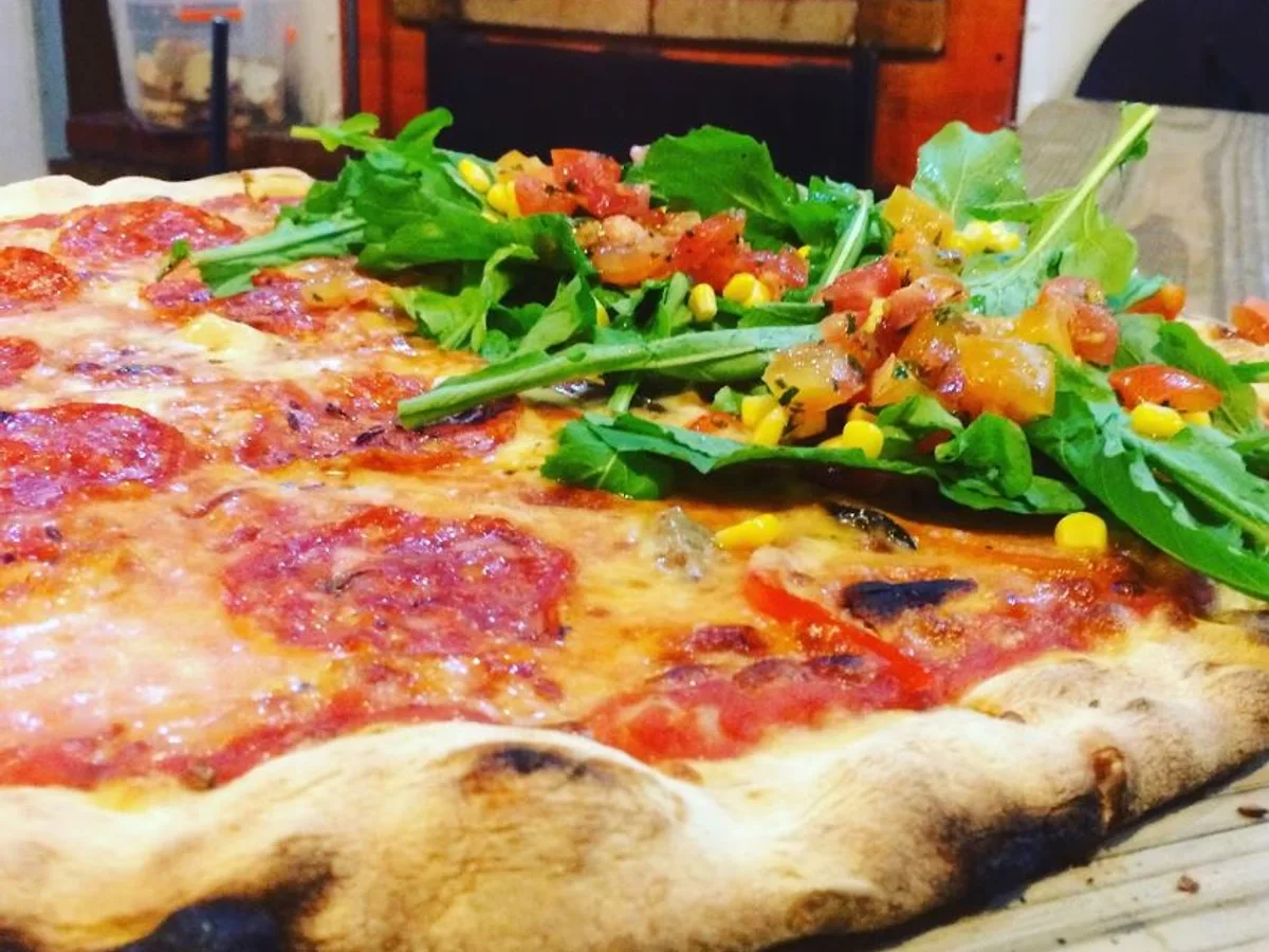 Wood-fired pizza topped with arugula, tomato and corn salsa at Pizza and Spaghetti House in Cabarete