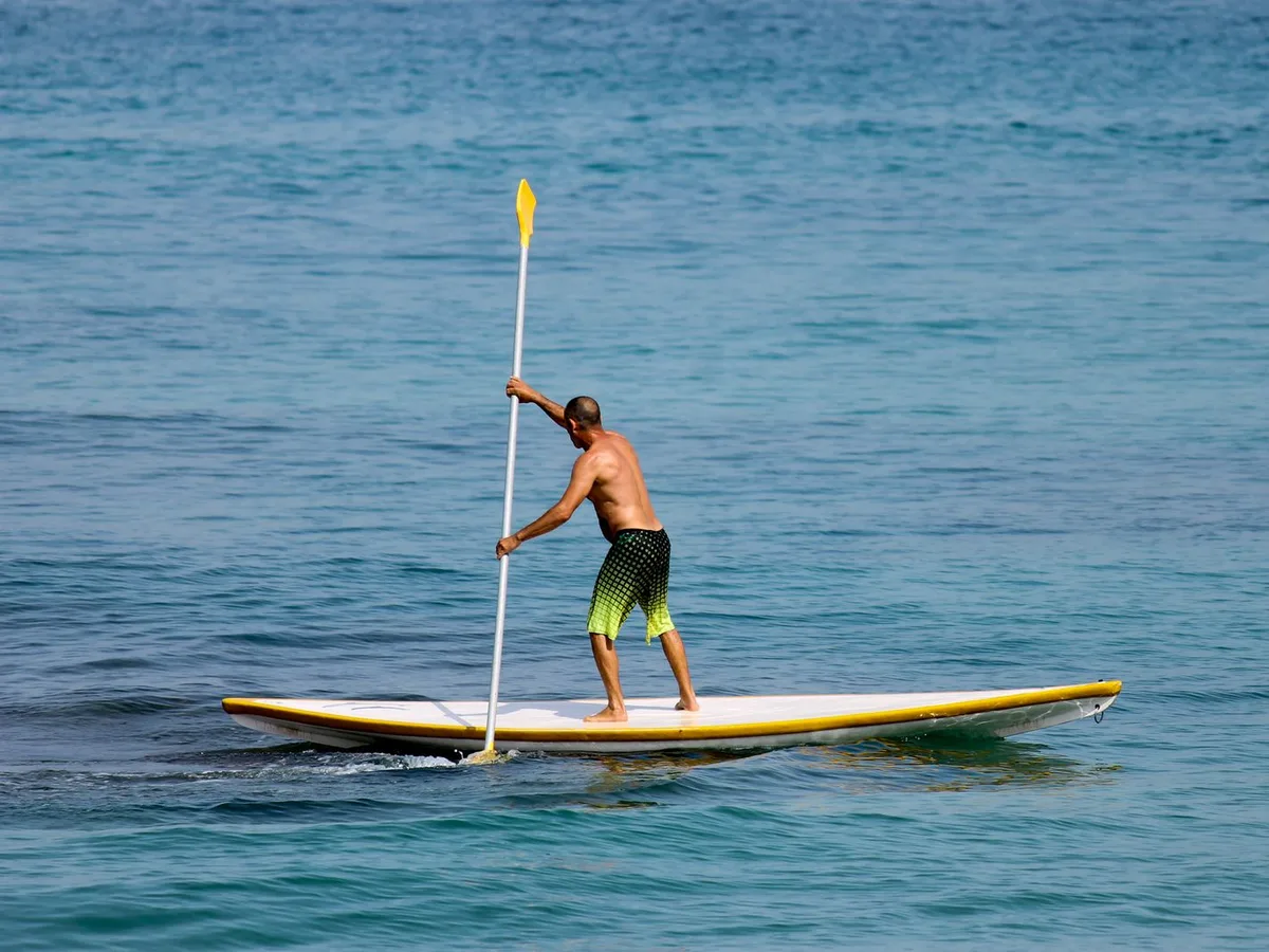 Person stand-up paddleboarding on calm blue water, a generic SUP photo