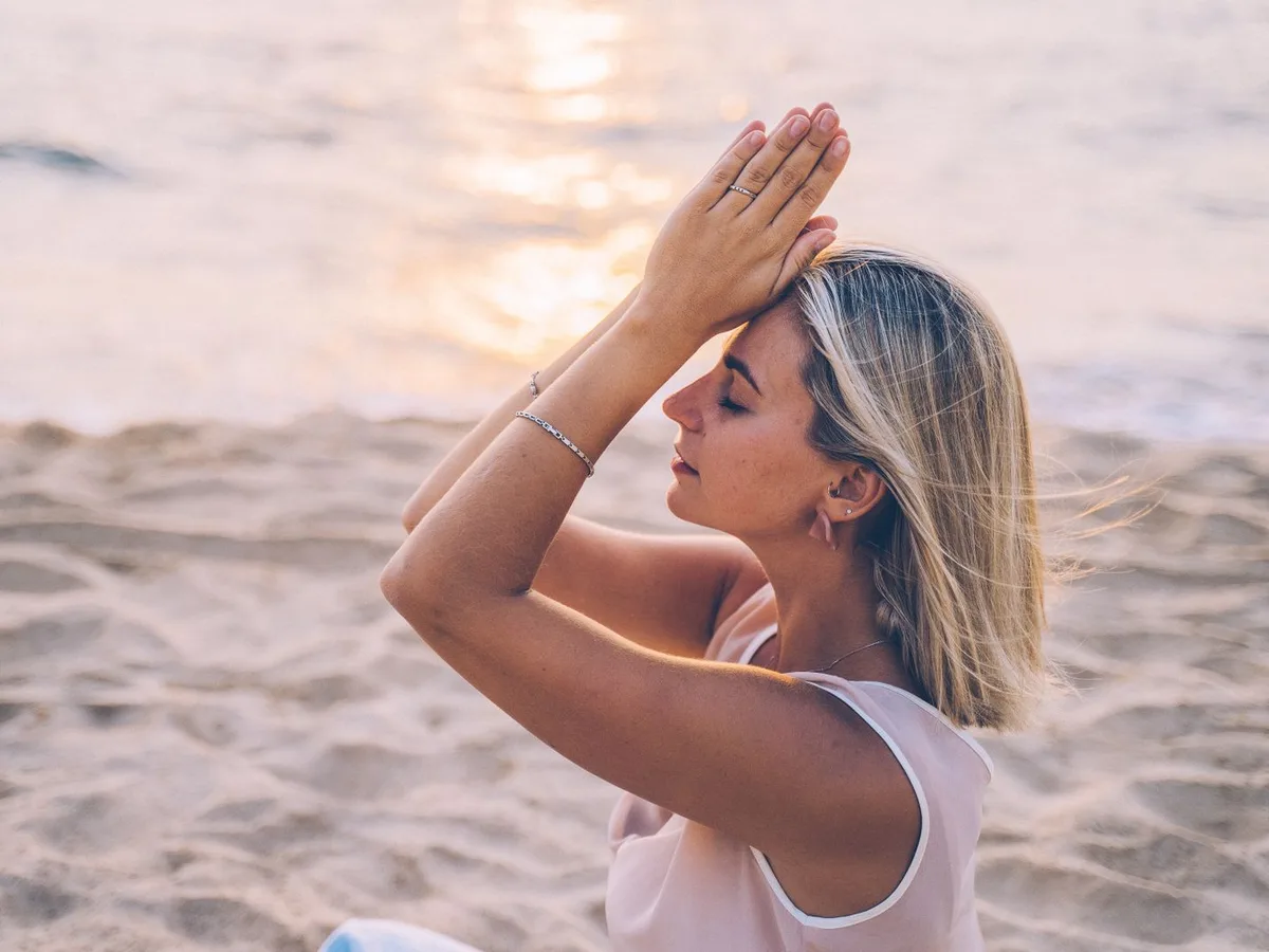 Woman practising yoga on the beach at sunset, a generic wellness photo